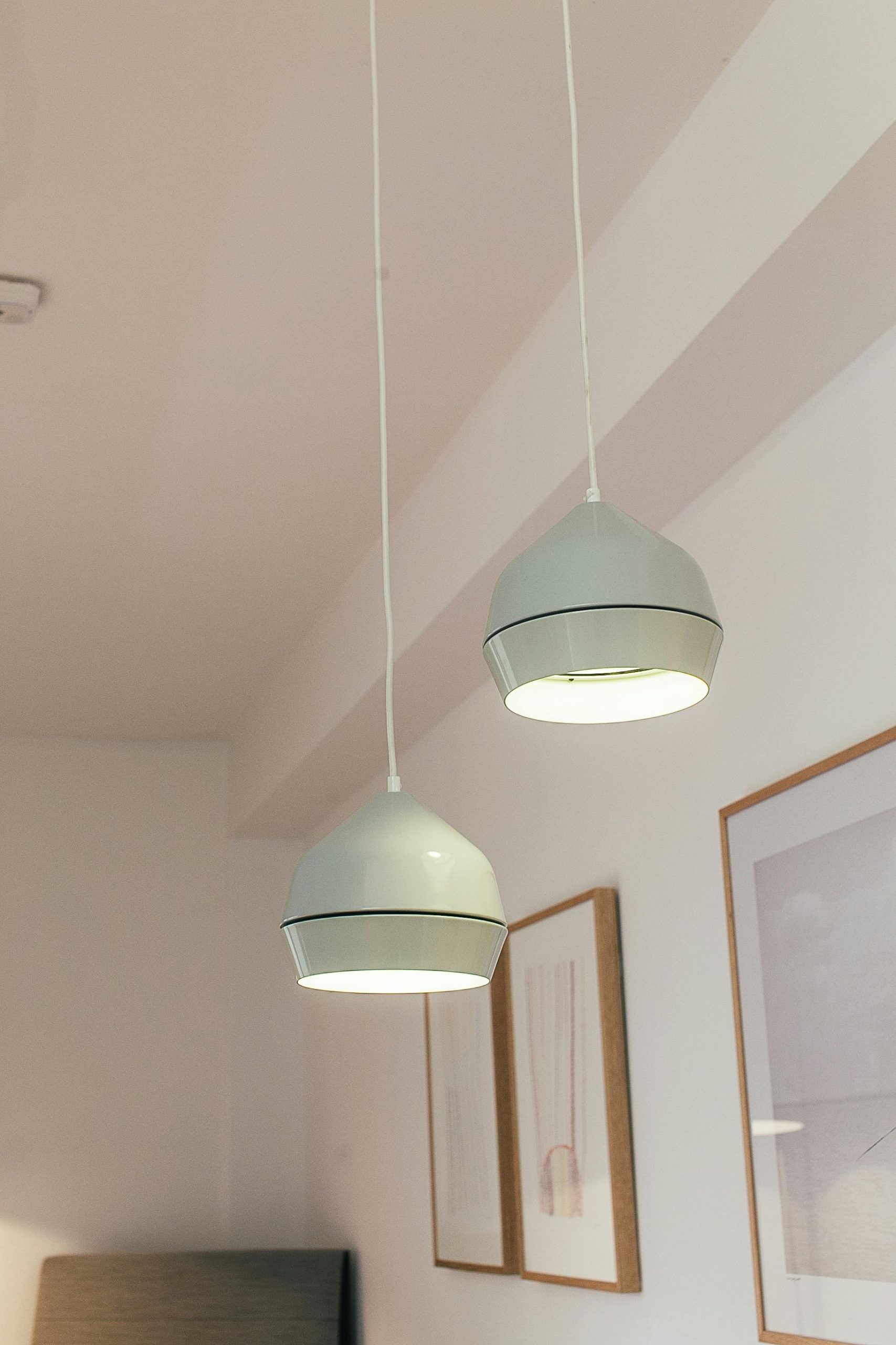 A minimalist interior featuring modern white pendant lamps and framed artworks.